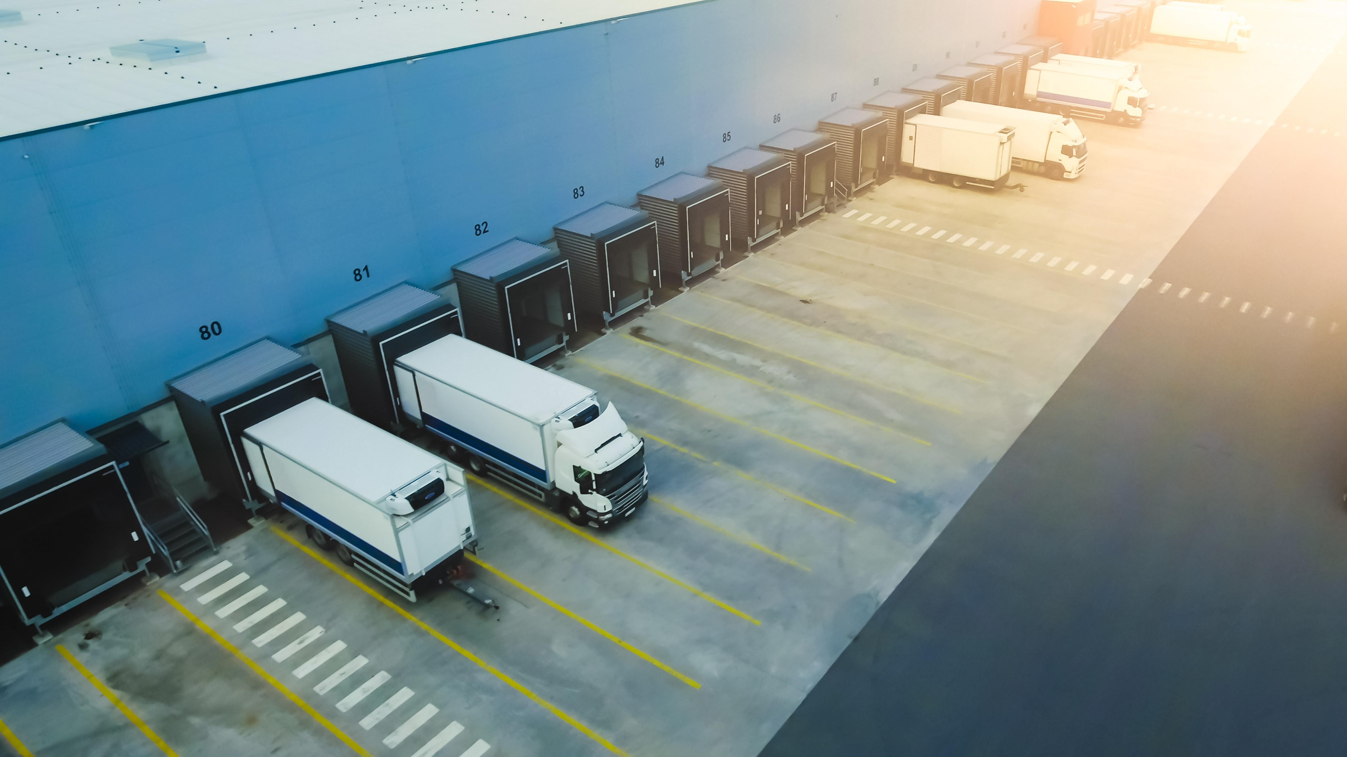 Aaerial shot industrial warehouse loading dock where many truck with semi-trailers load merchandise